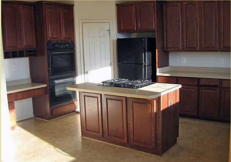 Kitchen renovation before with cherry cabinets and brown floors.