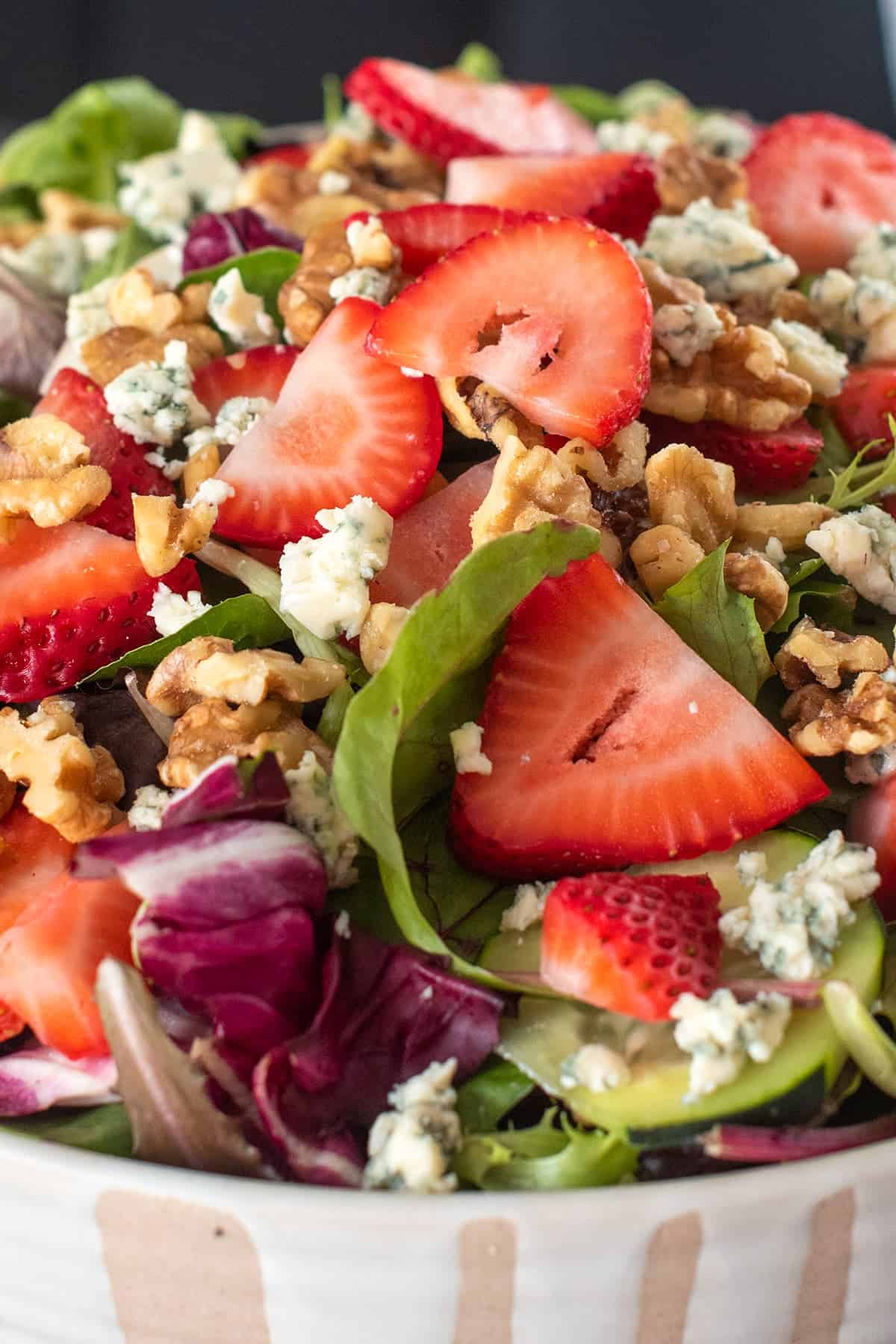 Closeup of Strawberry Spinach Salad in white bowl with beige accent.