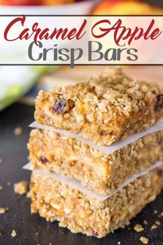 Apple Crisp bars stacked high with caramel dripping of the side and pieces of wax paper between each bar.