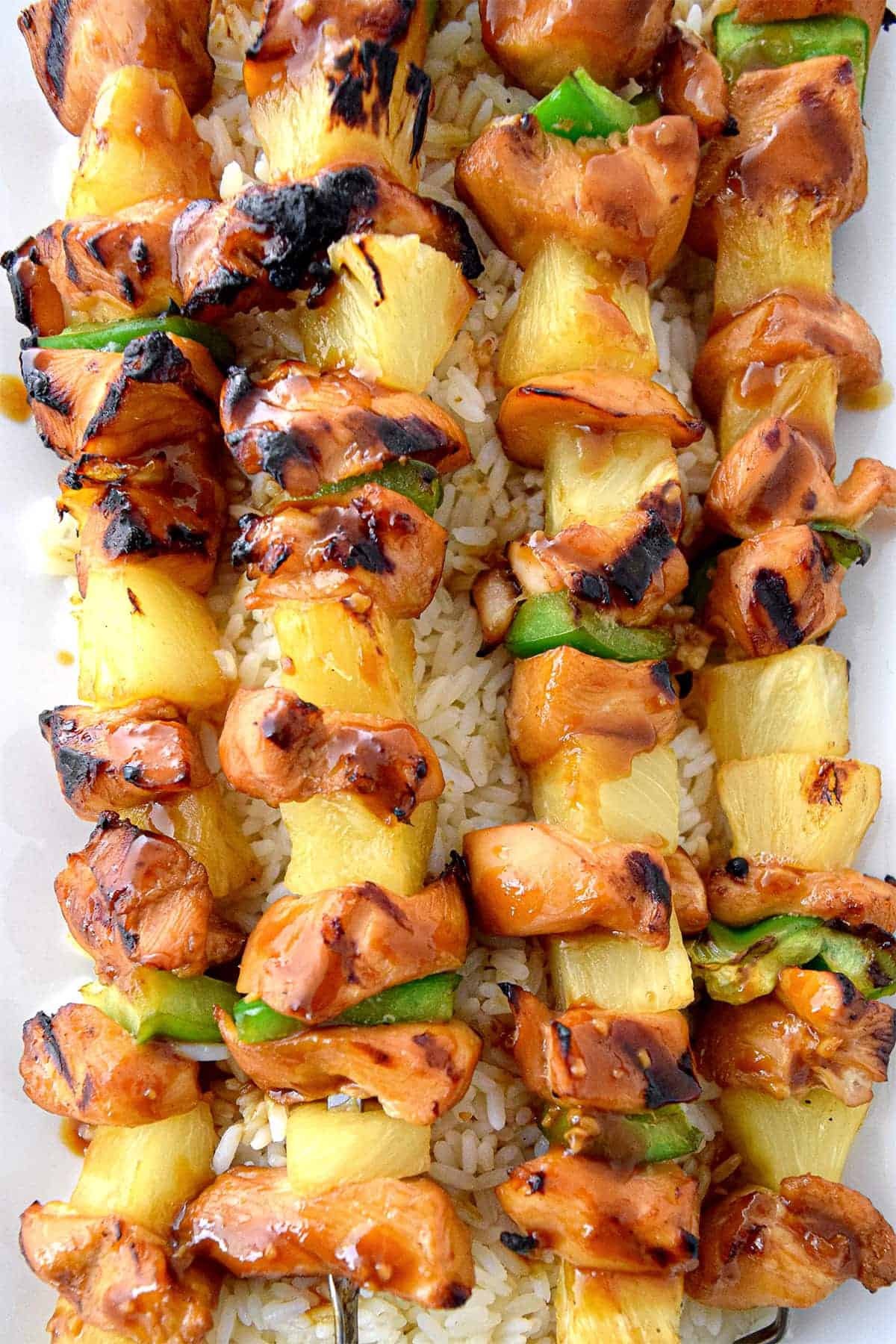 Teriyaki Chicken Kabobs overhead with pineapple and green peppers on a bed of rice.