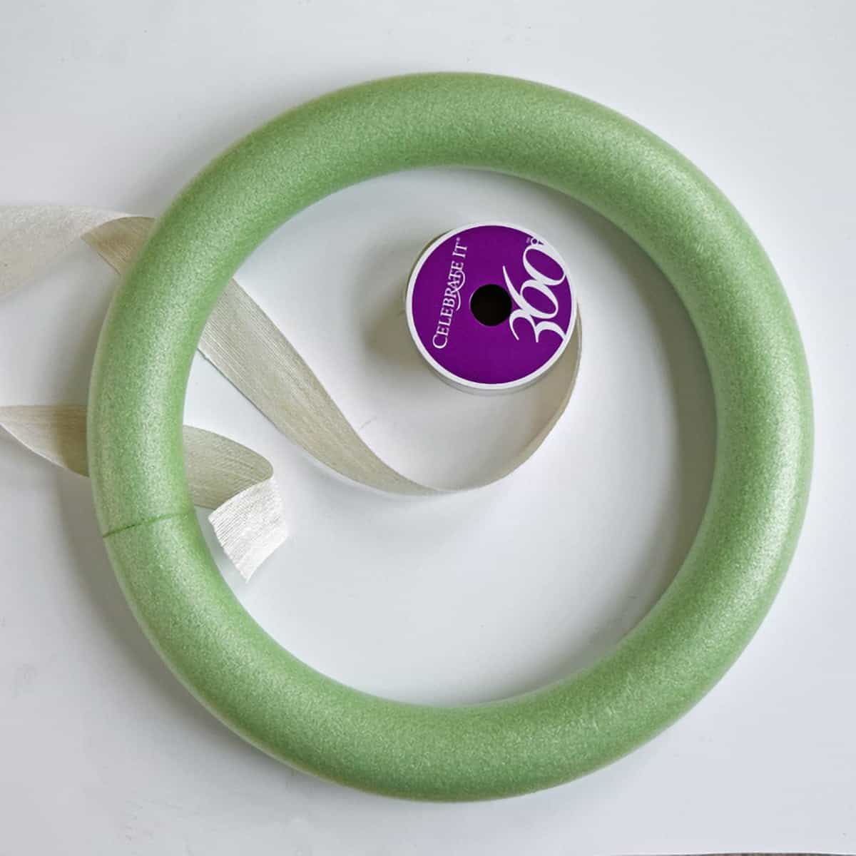 Green foam ring on white surface with spool of white ribbon