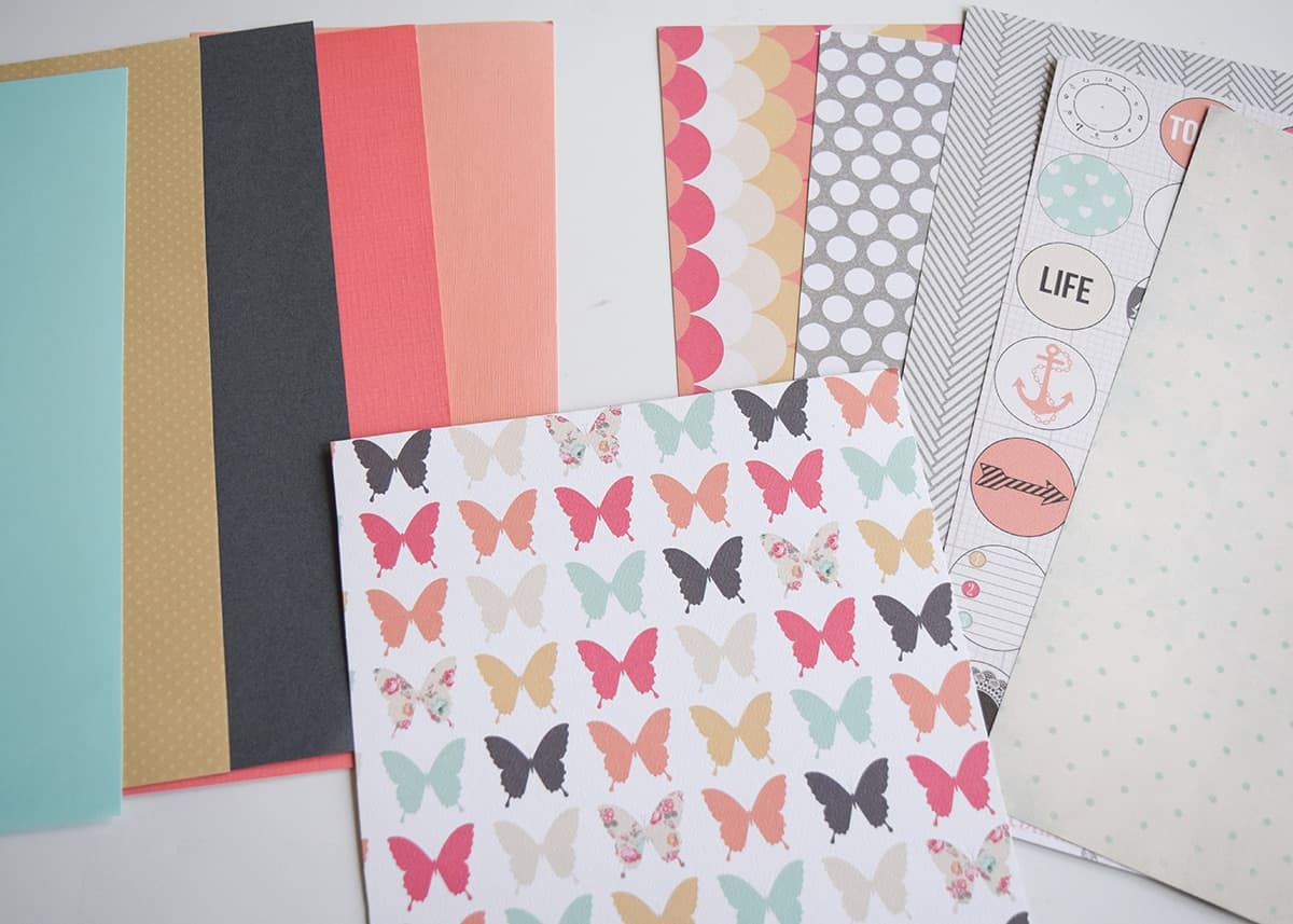 Collection of colorful craft paper with sheet of butterfly printed craft paper on top. 