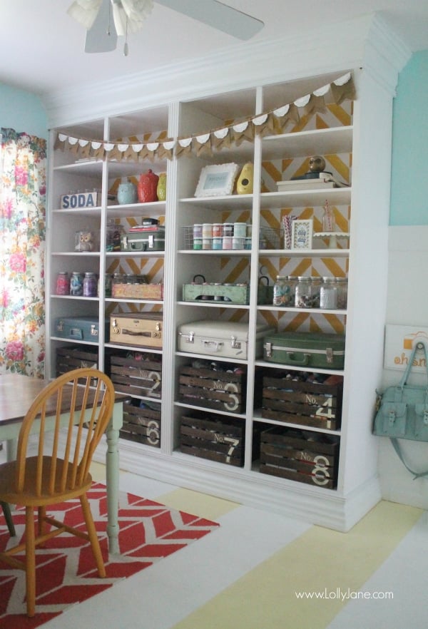 Built in shelving storage that uses painted crates and old luggage to showcase and office supplies organization