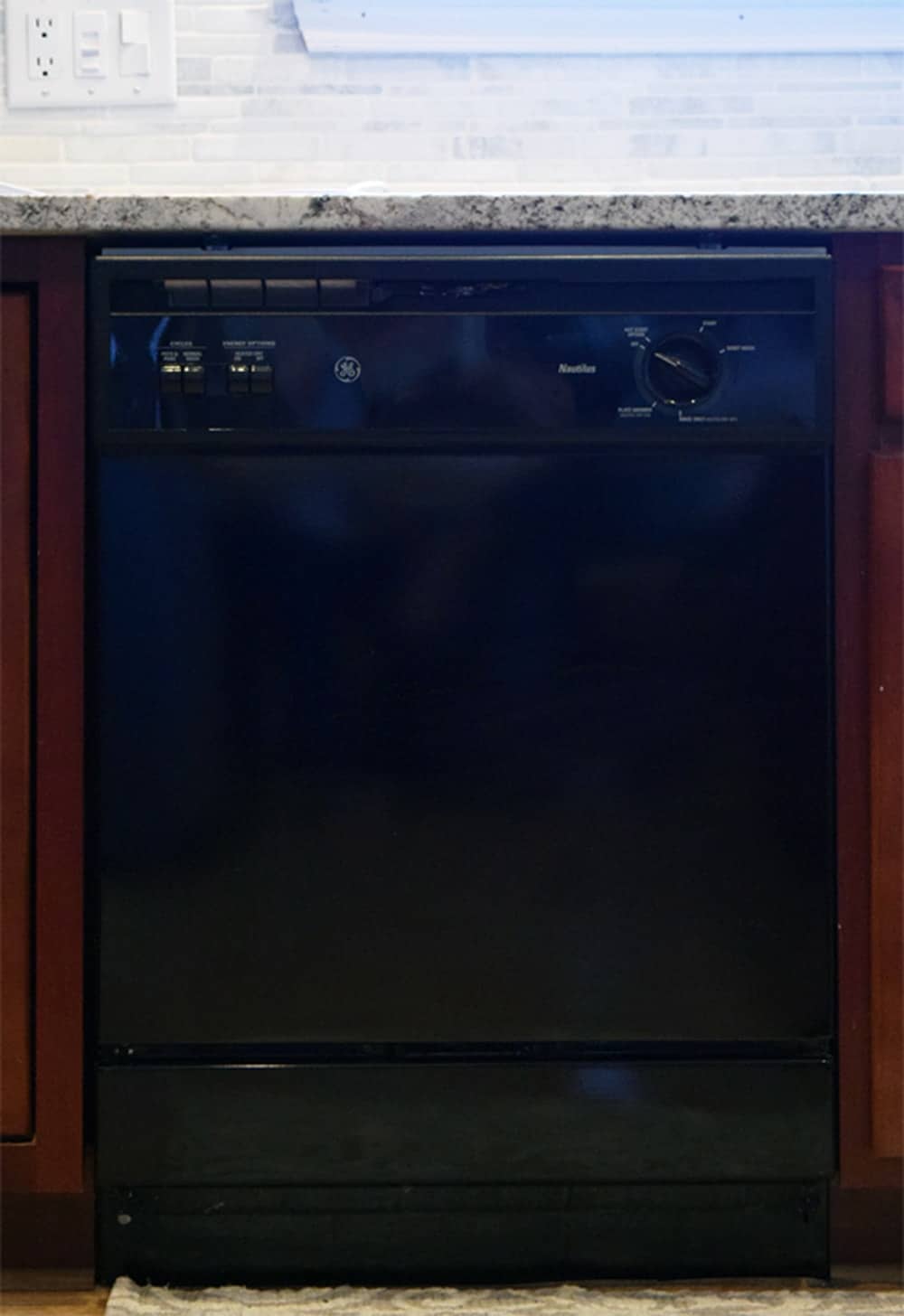 Black Dishwasher in kitchen with marble countertops. 