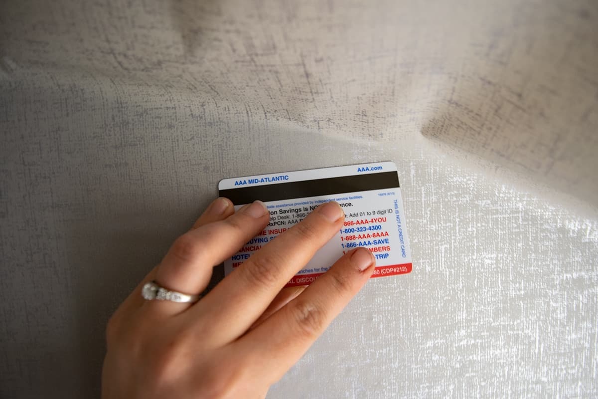 Hand removing air bubbles from applied contact paper with plastic card. 