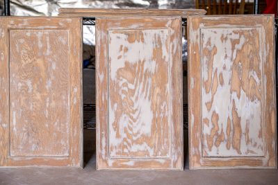 Three cabinet doors upright after sanding and filling wood grain.
