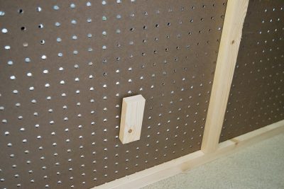 Close up of unfinished wood frame built around pegboard piece.