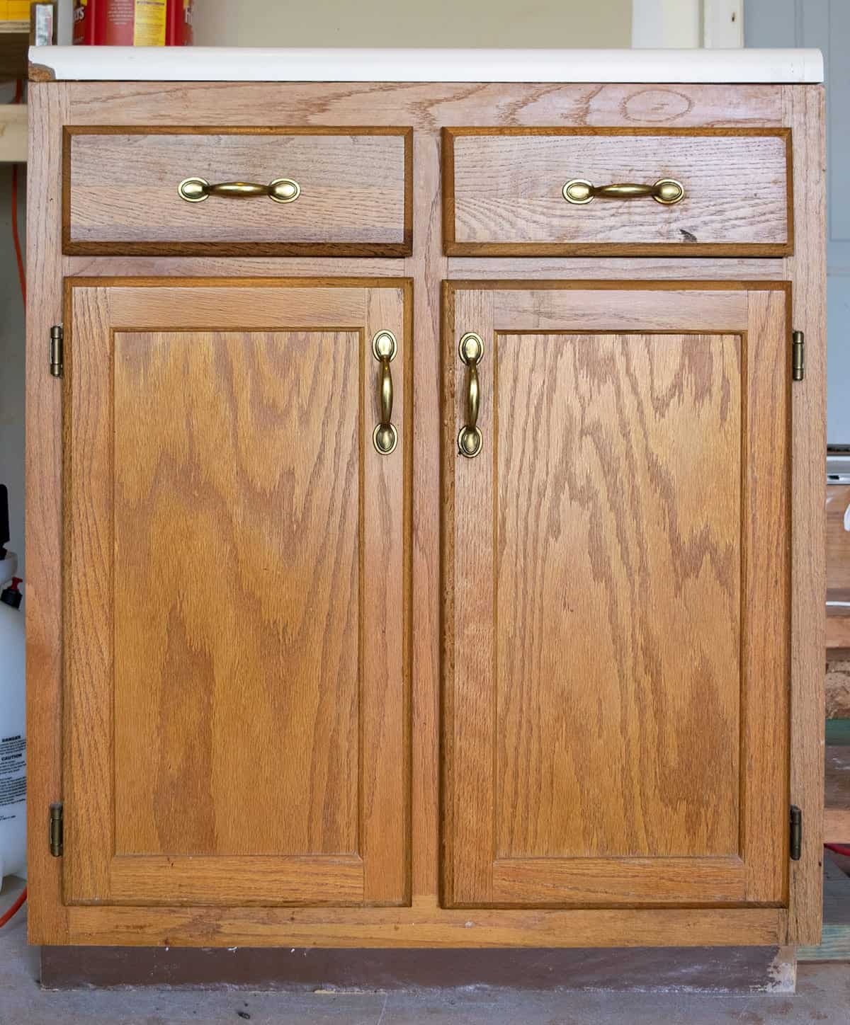 Old oak wood kitchen cabinet section in garage with coffee canister on top. 