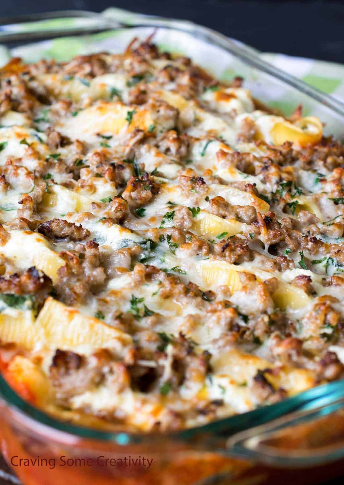 Baked Italian sausage stuffed pasta shells with ricotta and spinach in glass dish 