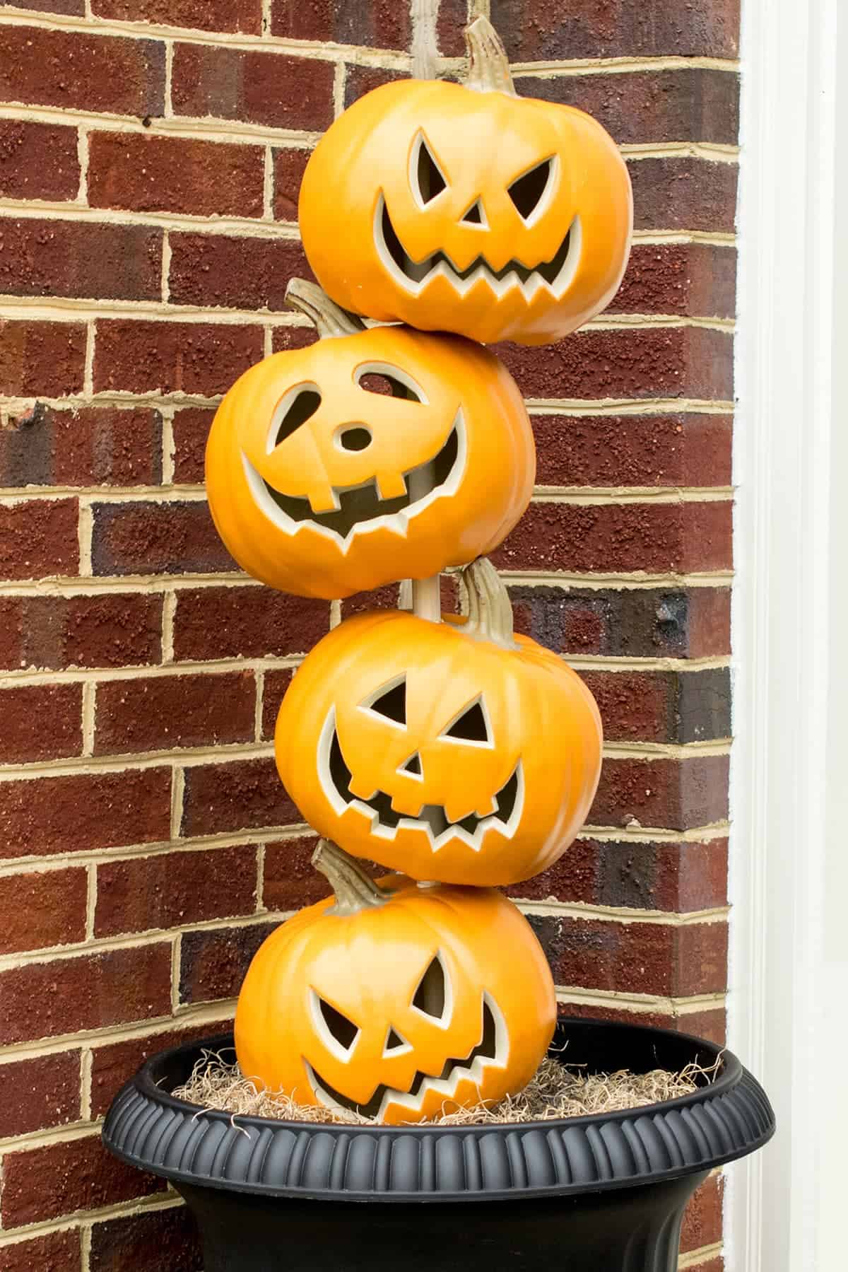 Stacked Pumpkin Heads to make a pumpkin topiary that is being used for Halloween front door decor.
