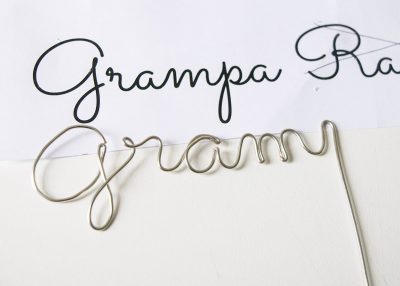 Paper with Grandma printed on it with wire being bent into place to match the printed font.