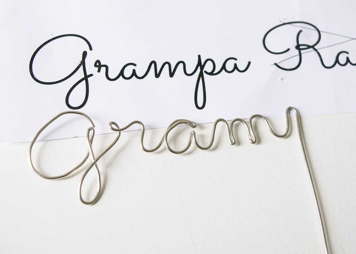 Paper with Grandma printed on it with wire being bent into place to match the printed font.