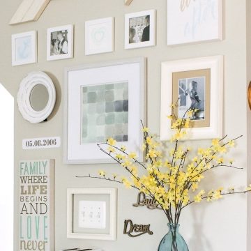 Gallery wall with a DIY arrow wall decoration, framed art, and glass vase with yellow flowers.