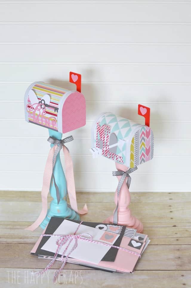 Candle stick mailbox crafts for valentines in pastel colors sitting in front of a wall.