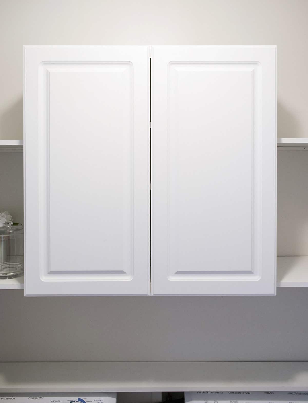 Plain white cabinets attached to white wall with simple shelving. 