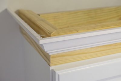 Cabinet crown molding on top of frame and attached to cabinet.