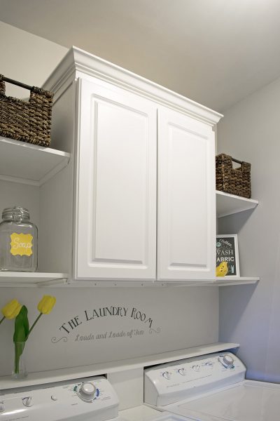 Laundry room cabinets and shelves above a washer and dryer in small laundry room.