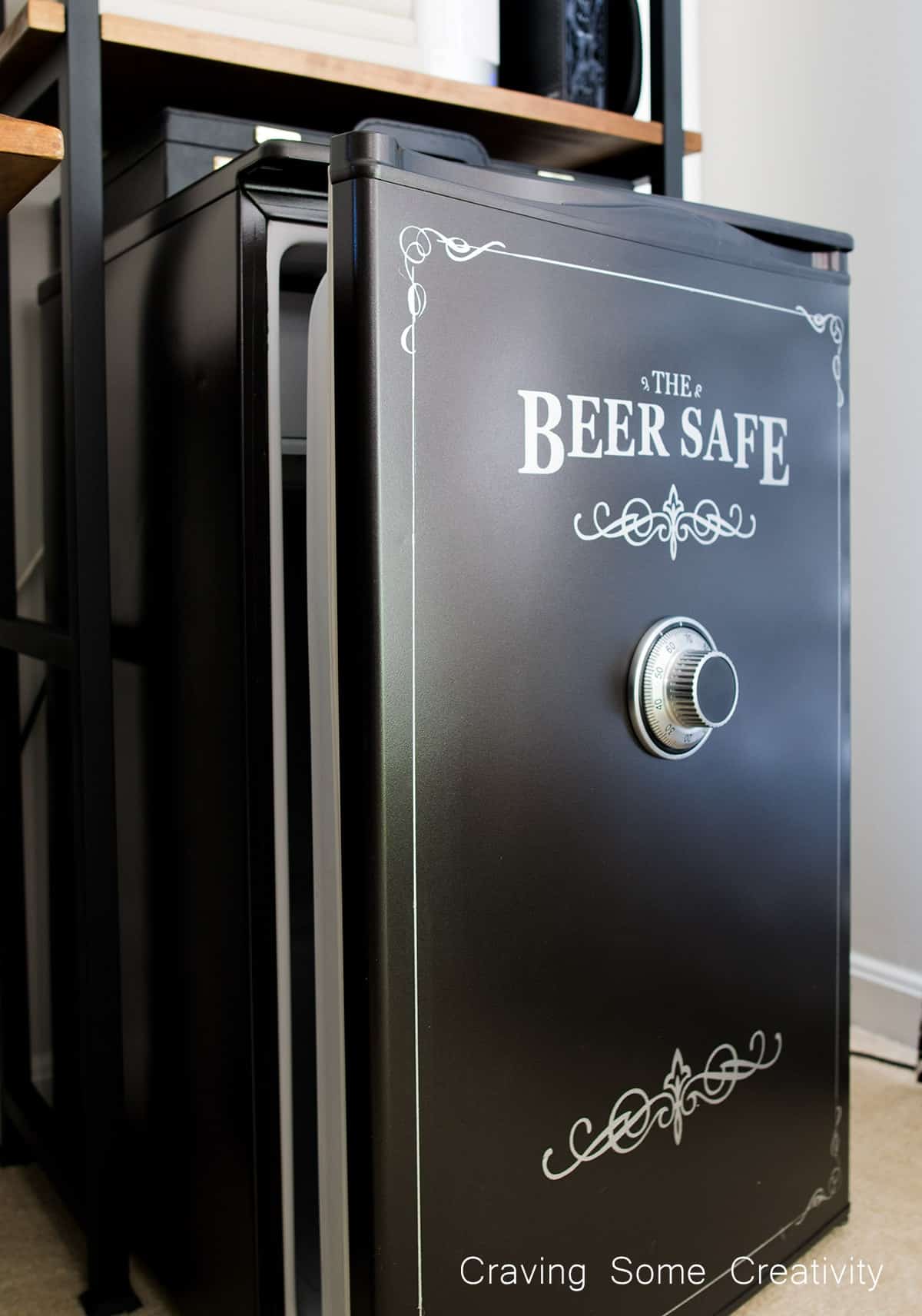 A black painted mini fridge with a beer safe motif and custom graphics with a safe wheel on the front.