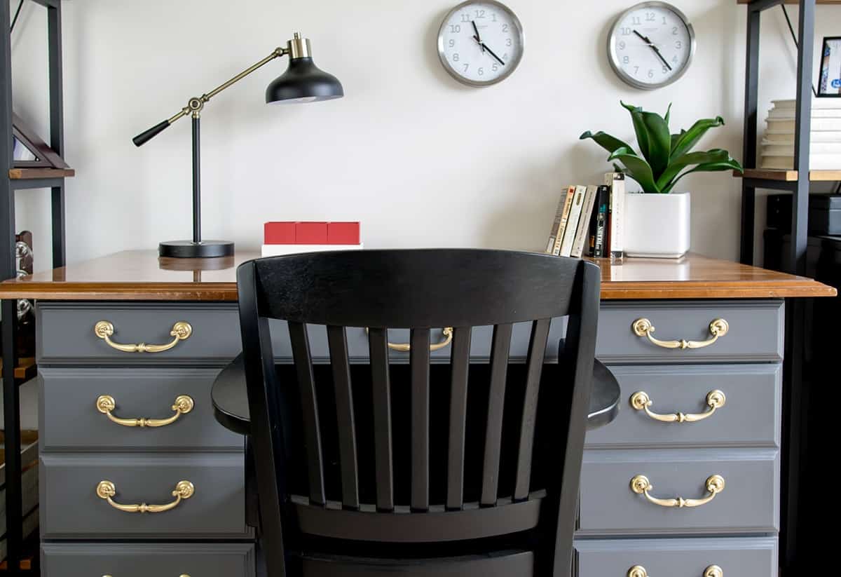 Antique desk with fresh gray paint makeover and polished brass hardware with black chair. 