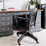 Grey painted desk with black chair in front in an office.