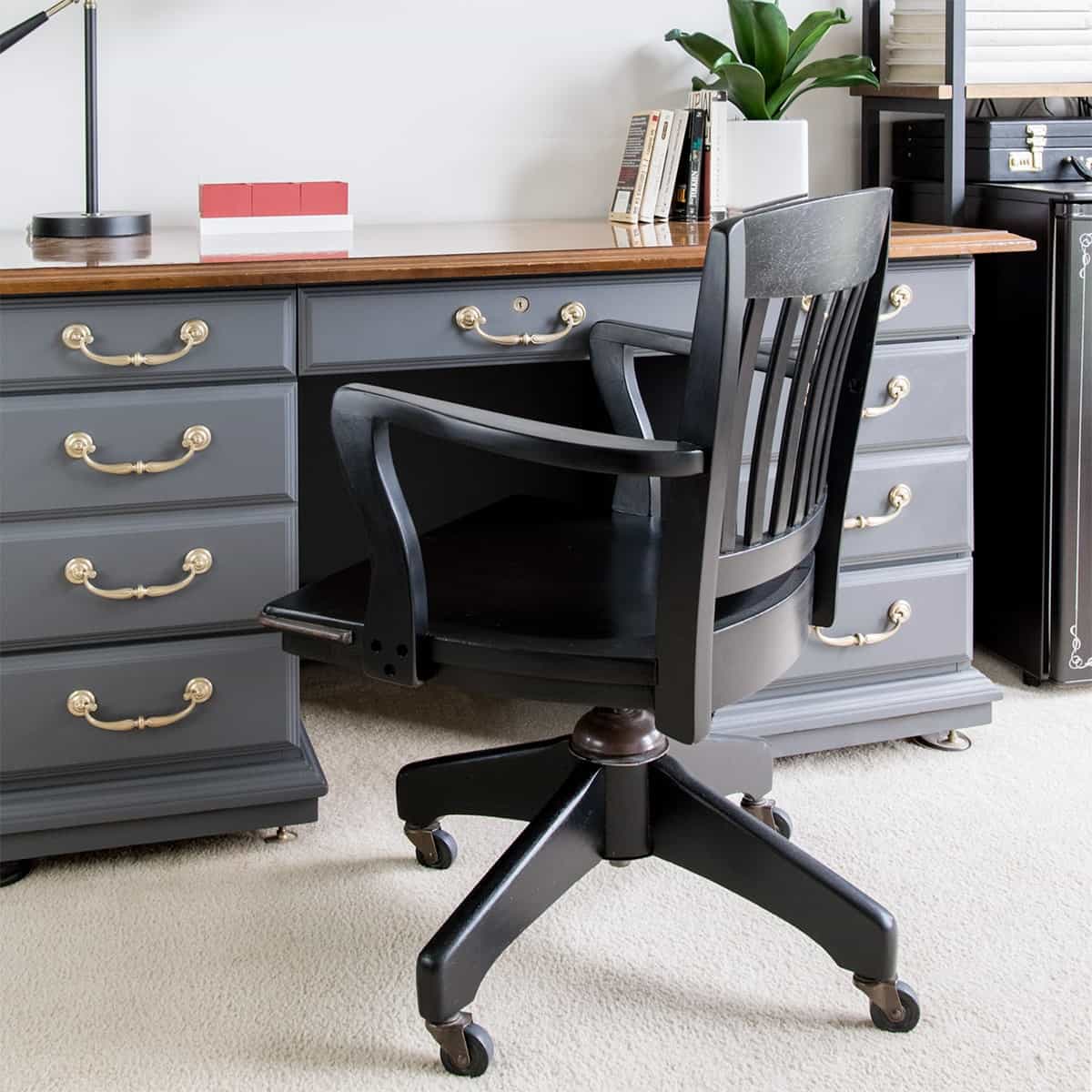 Black office chair in front of gray vintage desk with brass hardware after makeover. 