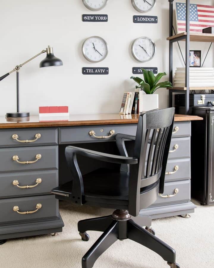 Masculine gray office with antique desk and black office chair. World clocks on the wall.