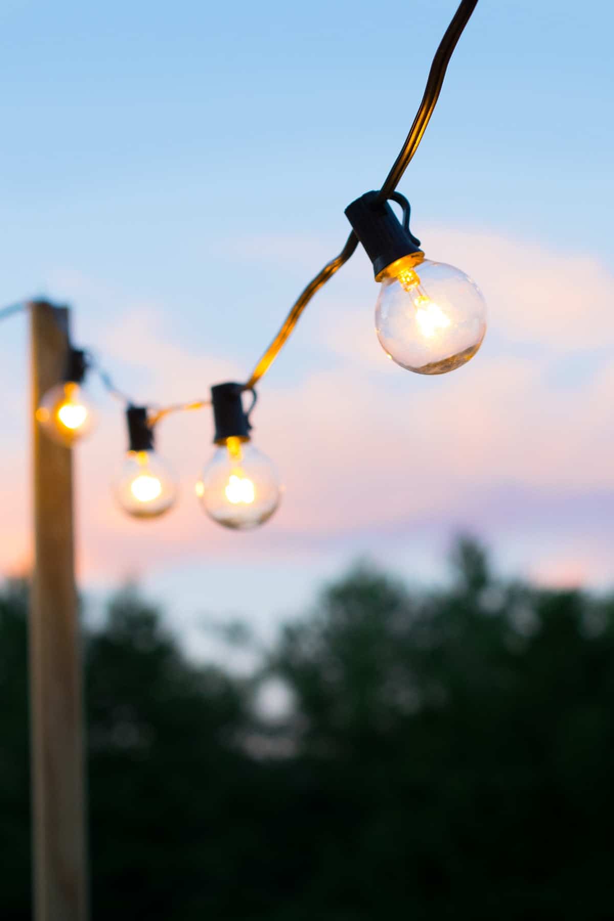 Outdoor wooden deck post with row of patio string lights.