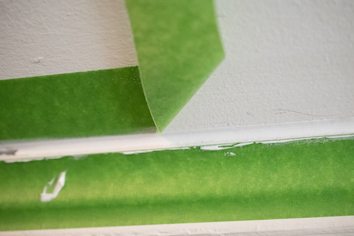 Removing painter's tape from caulked area on baseboard. 