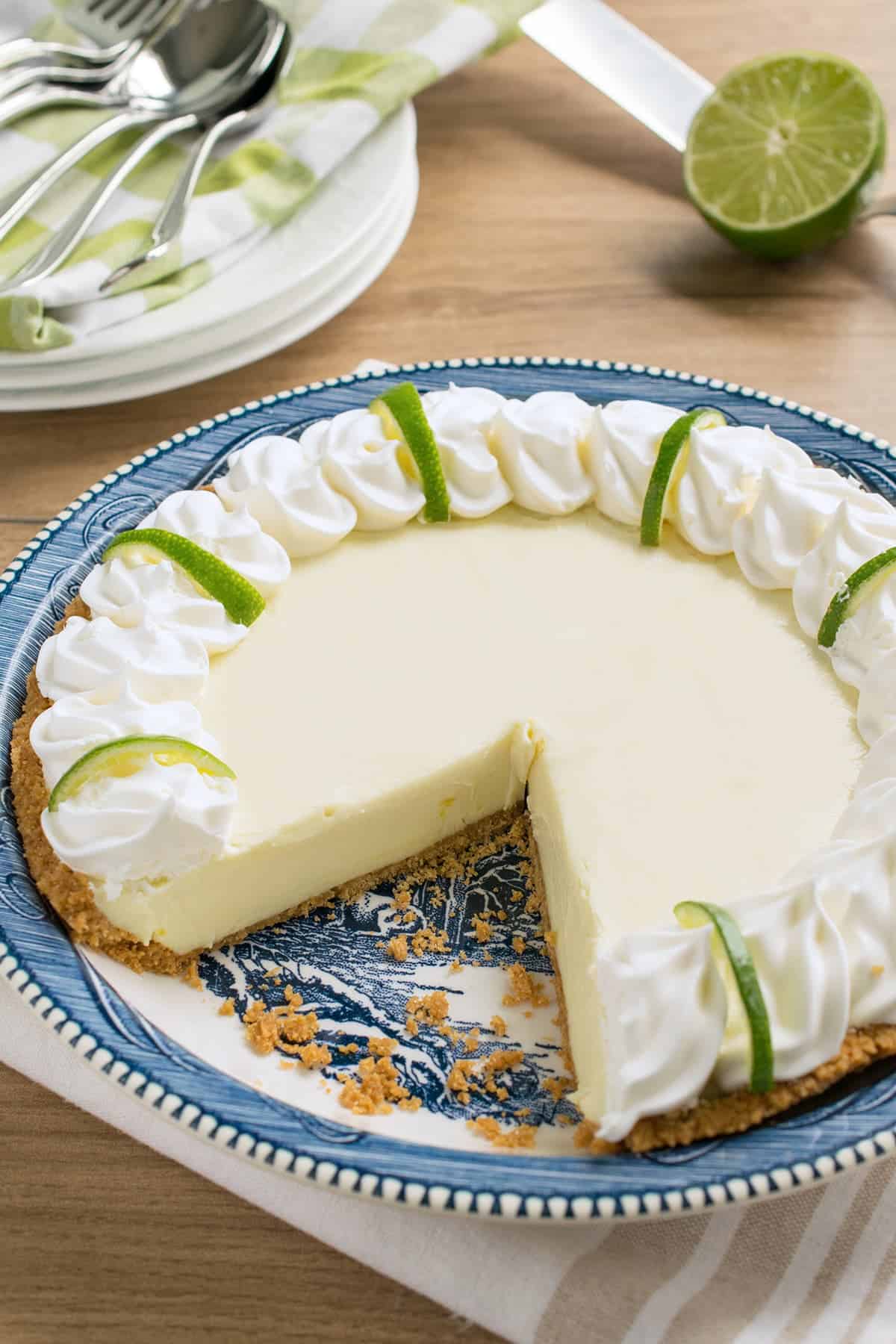 Key lime pie on blue plate with a slice cut out to show texture.