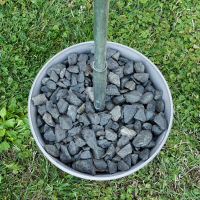 Plant container with gravel and metal pole inserted.