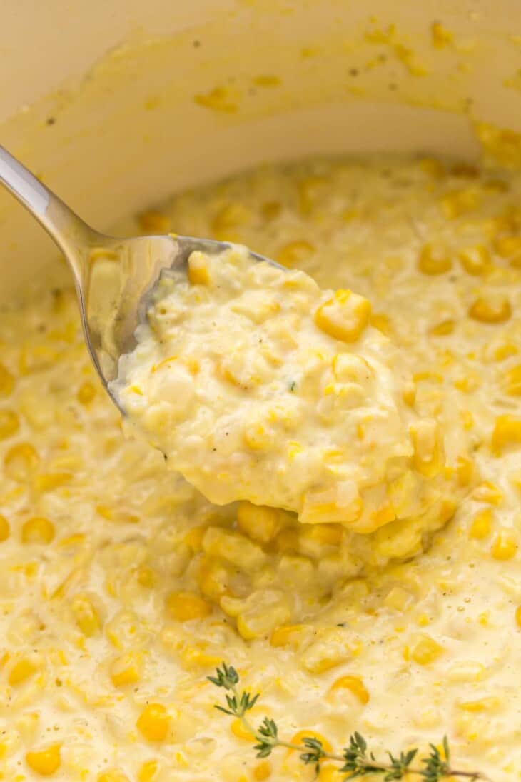 Closeup of spoon pulling creamed corn out of a pot.