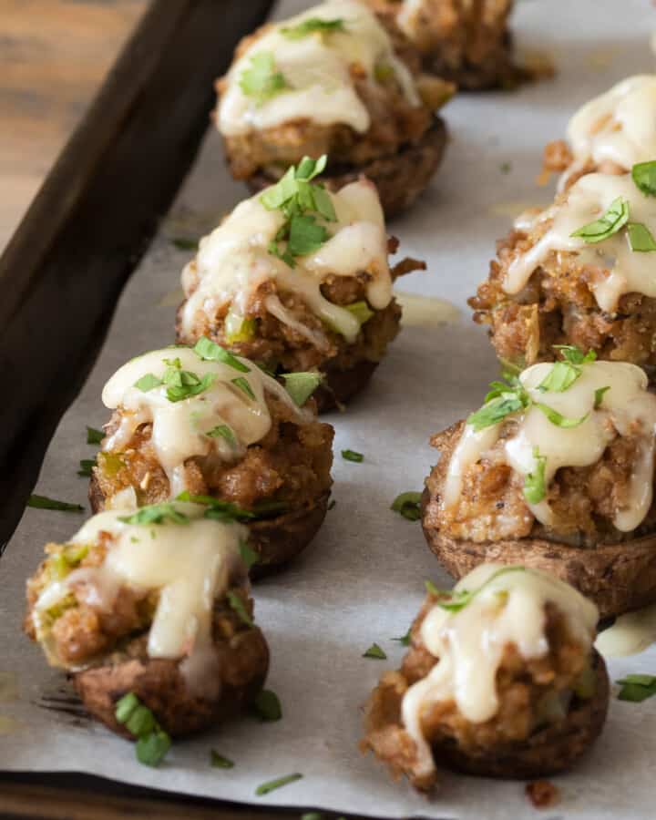 Sausage stuffed mushrooms on a sheet pan topped with swiss cheese and parsley.
