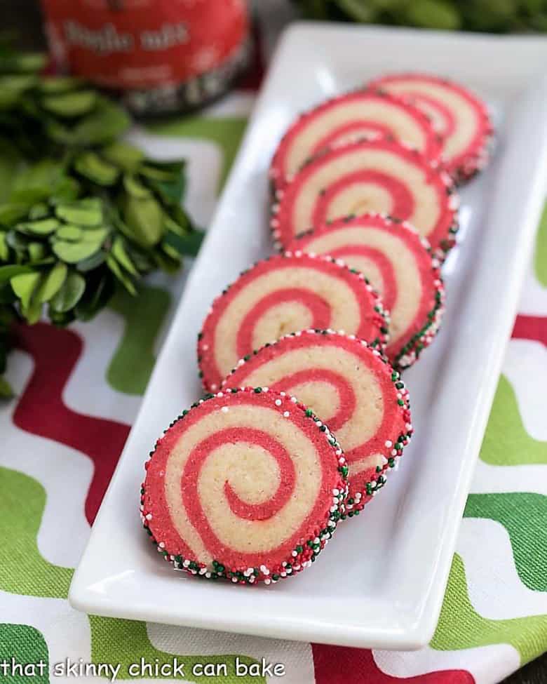 Christmas pinwheel cookies with red and white layers on a long white serving dish.