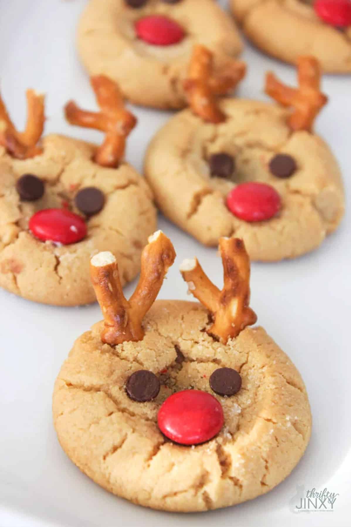 Peanut Butter Cookies made into reindeer faces on a white surface.
