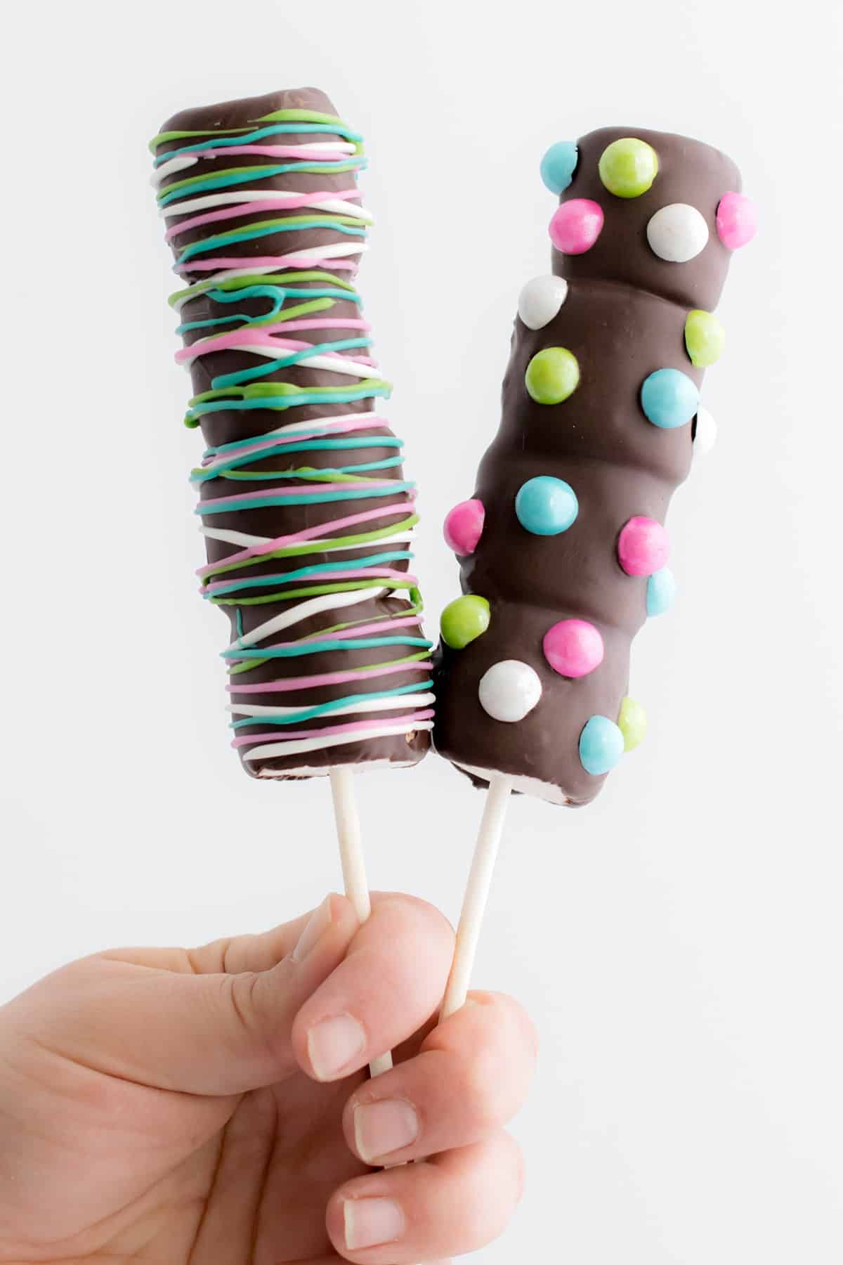 Two marshmallow pops dipped in chocolate and sprinkled with candies on top. how to make chocolate dipped marshmallow pops - easy decorating idea and fun to make with the kids. Add candies and colors!