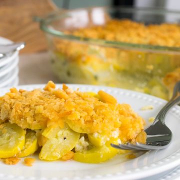 Squash casserole with ritz cracker toping as a side dish served on a stack of plates.