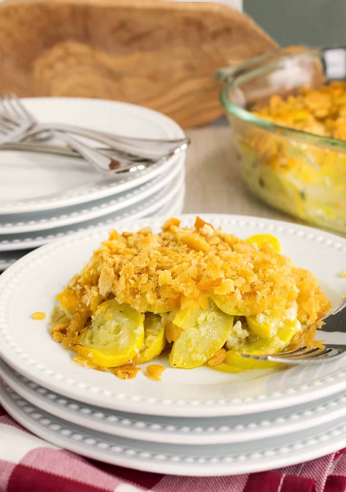 Squash casserole with ritz cracker toping as a side dish served on a stack of plates.