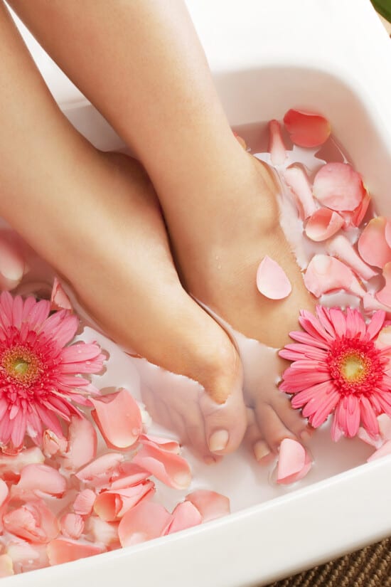 Feet in a foot bath with rose petals in water.