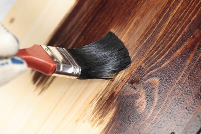 Using a paintbrush to add stain to wood.