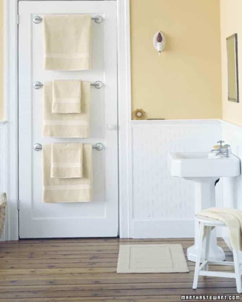 Towel rack on door in yellow bathroom.