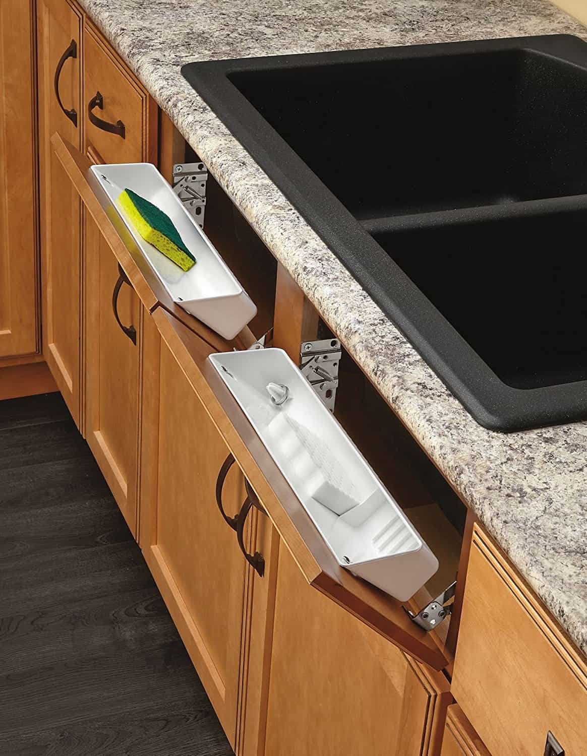 White hinged trays  installed inside kitchen sink cabinets for storing sponges and soap/ 