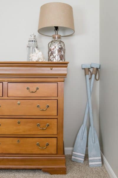 Soft blue whitewashed boating oars in bedroom corner by dresser.
