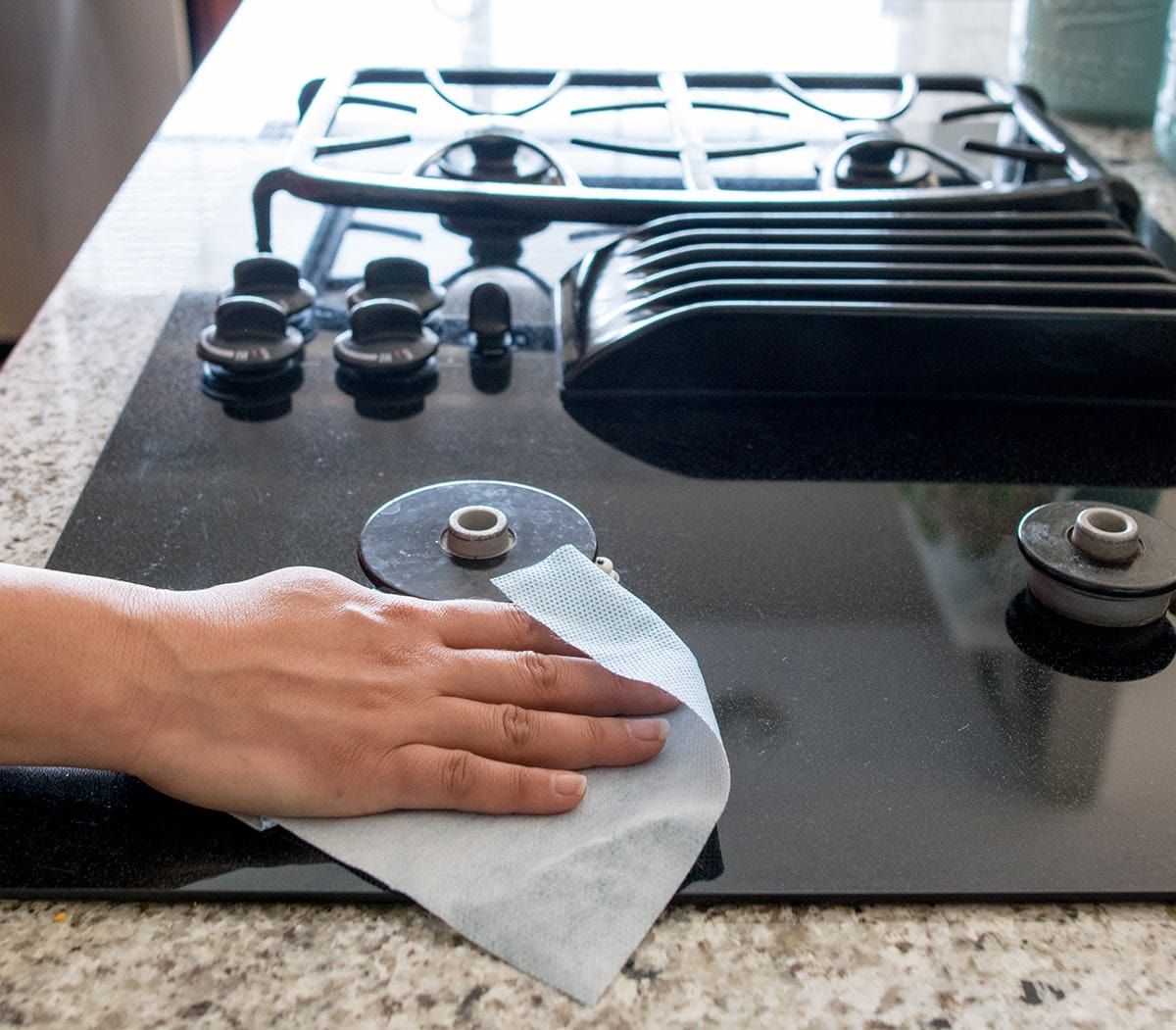 Black glass top stove surface wiped clean with white towel. 