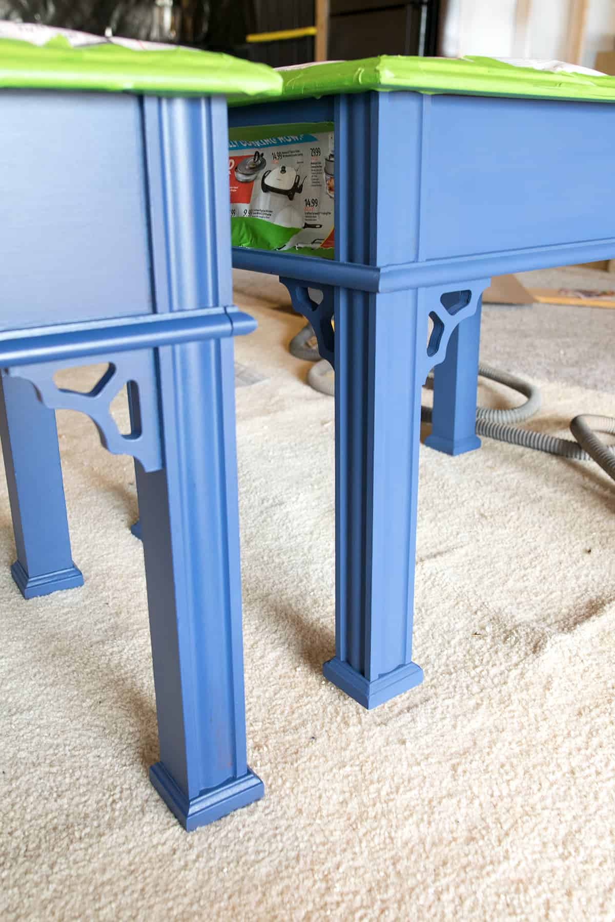 Difference in sheen for flat versus satin finish on two blue side tables 