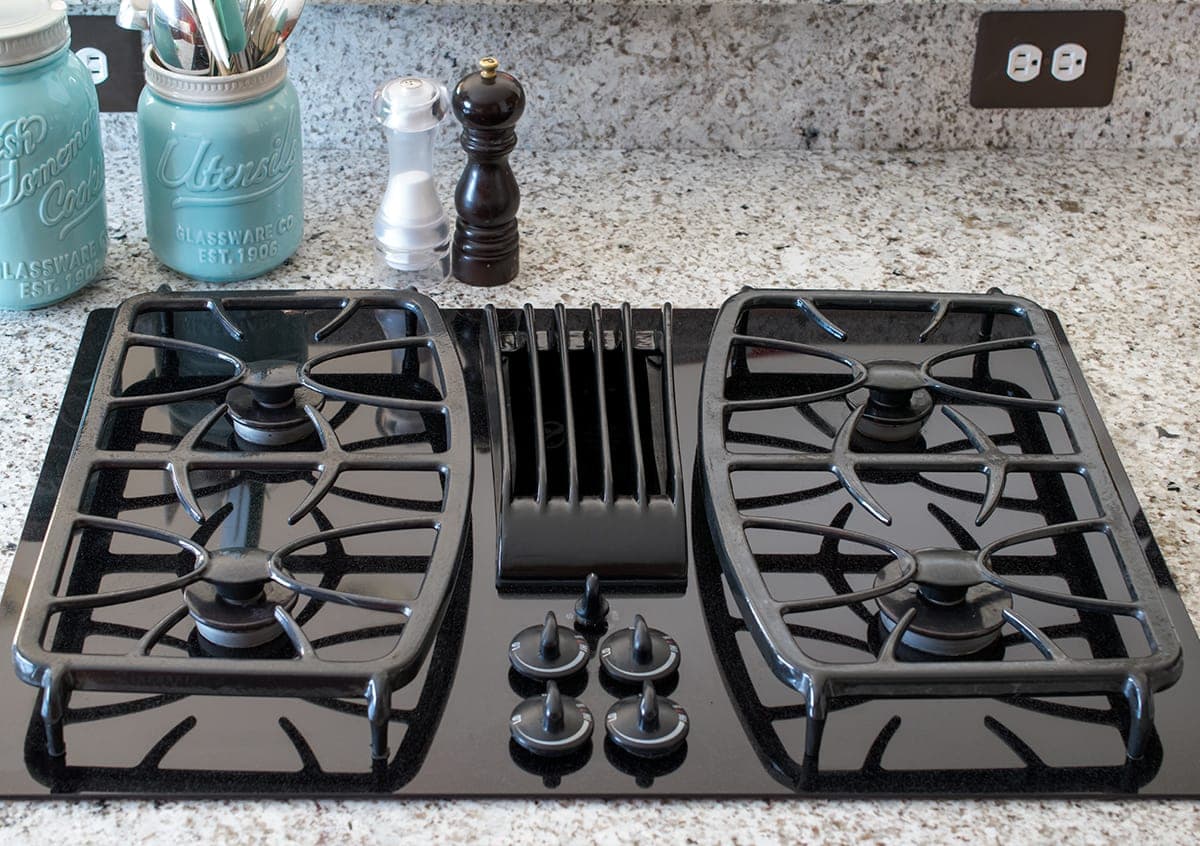 Overhead of clean glass stove top with gas burners.