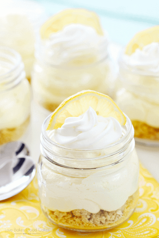 No bake mini lemon cheesecakes in adorable mini mason jars topped with swirl of whipped cream and lemon slice