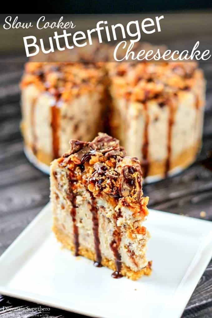 Slice of creamy butterfinger cheesecake on white plate topped with chopped butterfinger candy pieces, drizzled with chocolate
