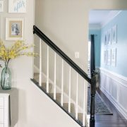 Completed oak painted stair railing with black handrail and white balusters.