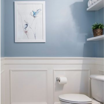 Blue powder room with wainscotting wall and marble floor.