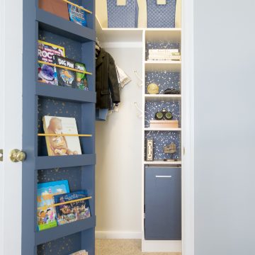 Toddler closet with open door revealing closet organization, shelving, laundry hamper, and book shelf on the back of the door.